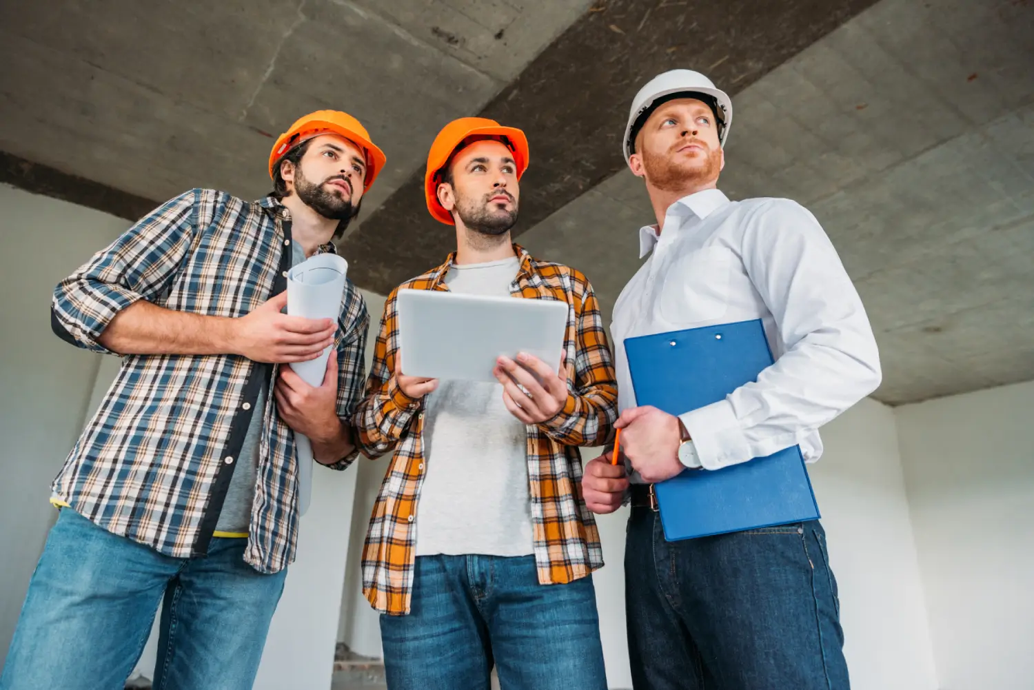 Three Manufacturing workers wearing element and holding arcthitectural plans